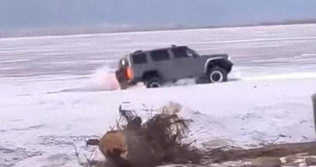 越野车水库冰面练漂移，冰层破裂车轮被冻6小时，吊车深夜将车吊出，有人用锤子破冰帮助脱困