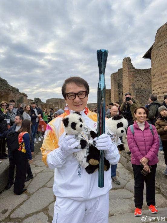 成龙穿越庞贝古城传递米兰冬奥火炬，手持熊猫玩偶与火炬合影