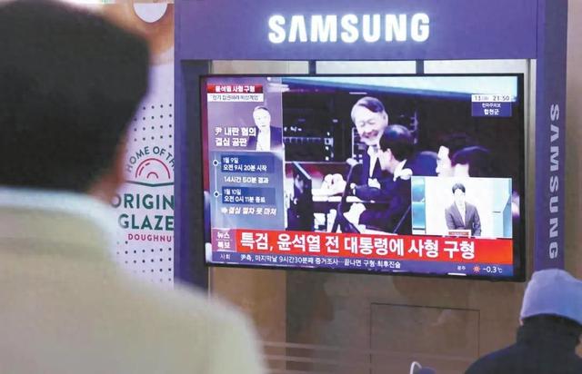 韩媒报道称，韩国前总统尹锡悦在13日的庭审中发出冷笑。图为当天首尔民众收看庭审有关报道。 （图片来源：纽西斯通讯社）