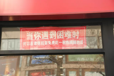 老張拉麵館店外張貼的標語上寫著：「當你遇到困難時，可以在老張拉麵免費吃一碗熱騰騰的面。」首都文明辦供圖