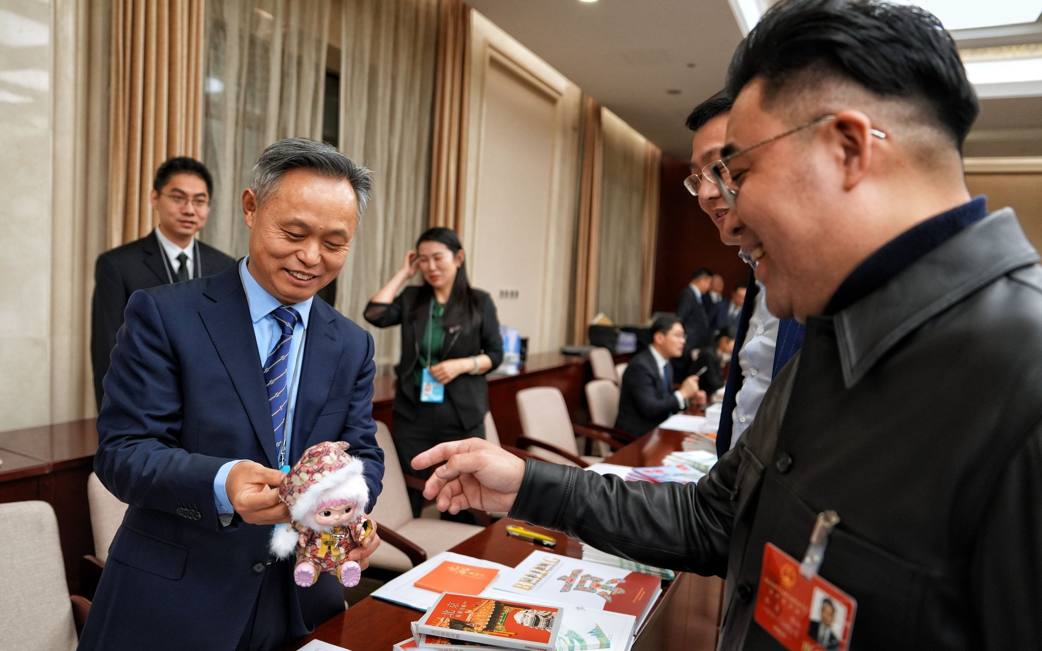 北京市文旅局局長郭懷剛（左）向人大代表展示具有馬年元素的潮玩。新京報記者 陶冉 攝