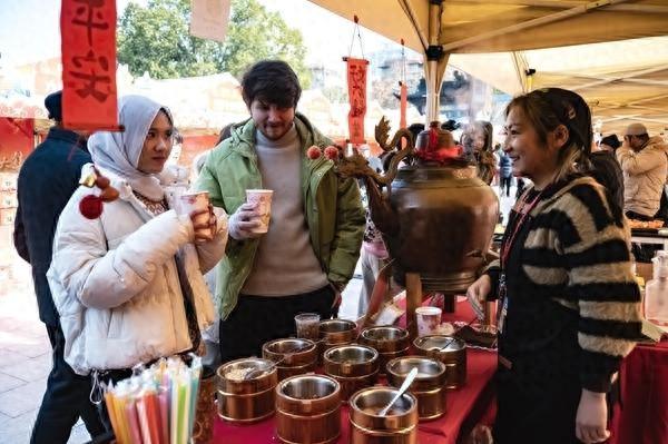 1月23日,江苏南京,外国游客在年货大集上品尝中国美食。视觉中国供图