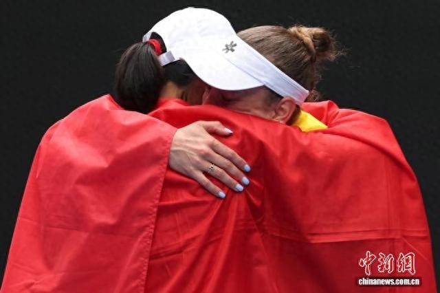 张帅(右一)夺冠后身披国旗，与比利时搭档梅尔滕斯相拥。图源澳大利亚网球公开赛官方微博