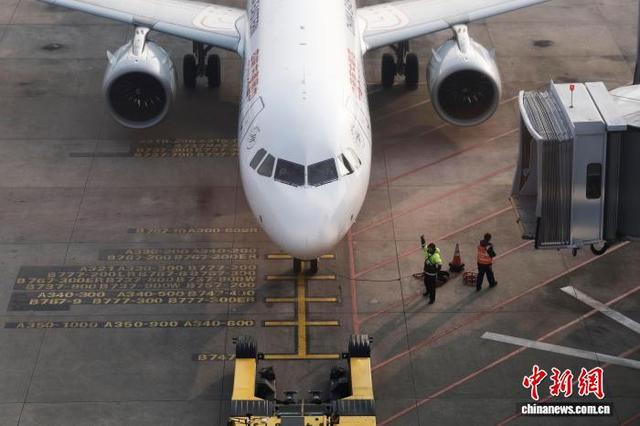 2月2日，在上海虹桥国际机场，东航机务人员引导拖车将飞机推离登机口。中新社记者 殷立勤 摄