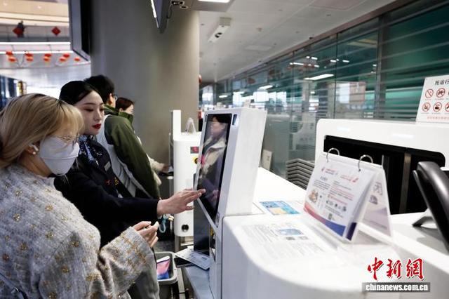 2月2日，在上海虹桥国际机场T2航站楼内的东航自助托运柜台，工作人员帮助旅客办理行李托运手续。中新社记者 殷立勤 摄