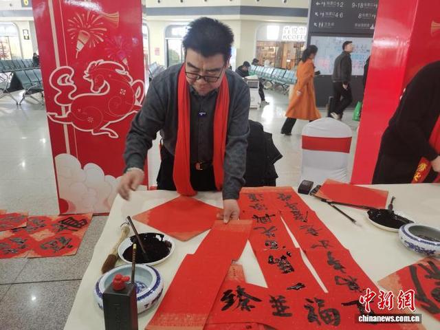 图为春运首日，在呼和浩特东站为旅客写春联的书法家张树天。 中新网记者 李爱平 摄