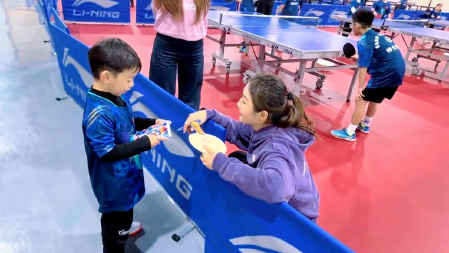 陈梦为小朋友签名球拍，萌娃淡定忘签照片