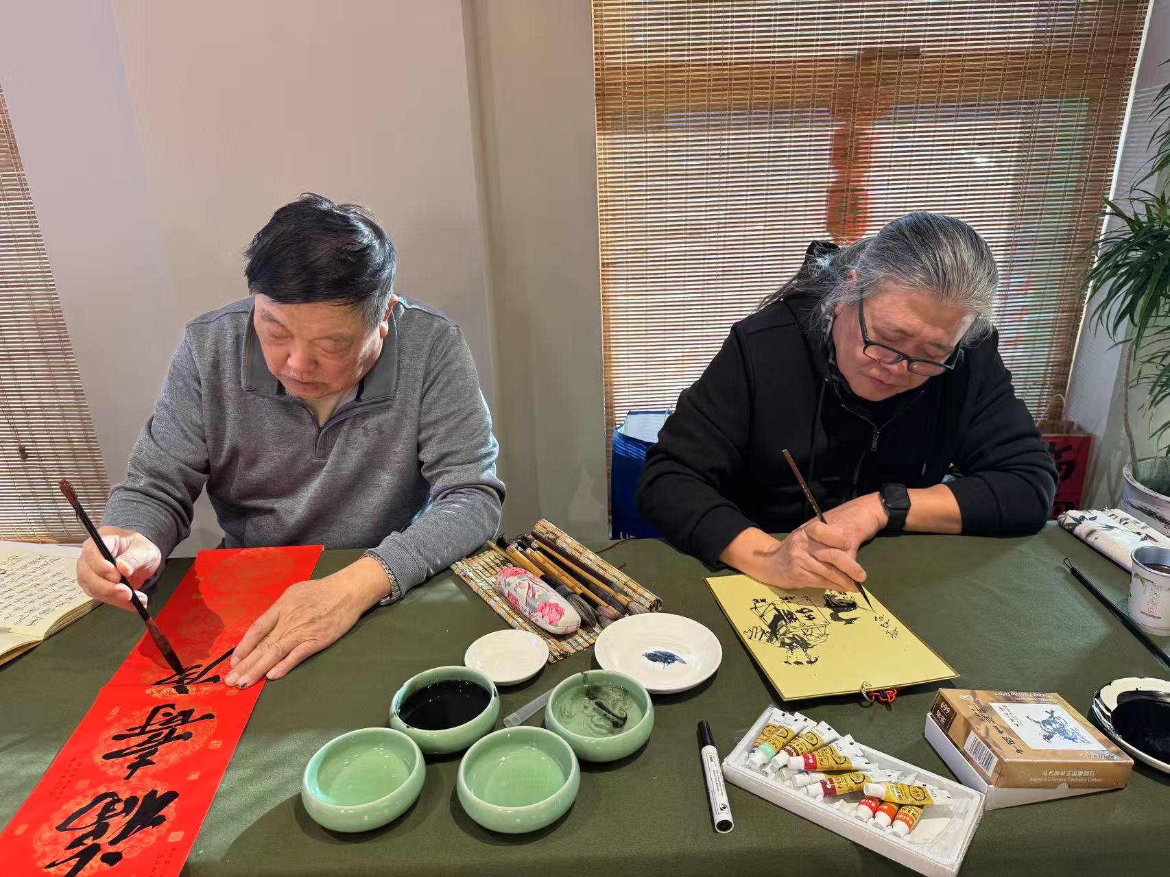 桑治銀山（左）、楊信（右）等嘉賓現場寫春聯、畫年畫。新京報記者徐彥琳 攝