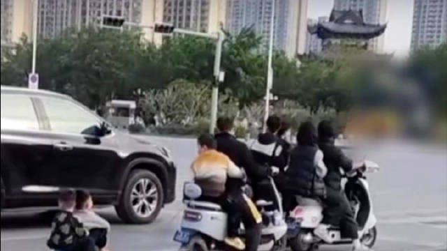 男子骑电动车拖行两坐滑板孩子