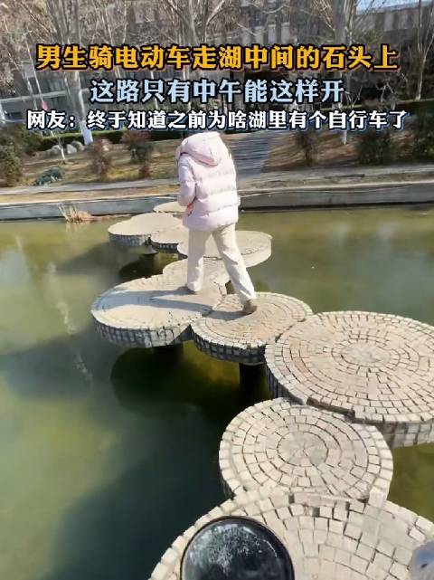 男生骑电动车走湖中间的石头上，安全第一！