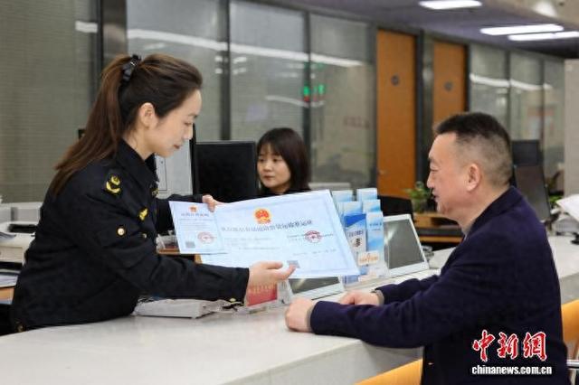 图为重庆市九龙坡区市场监管局许可窗口工作人员向企业负责人颁发重点液态食品道路散装运输准运证。重庆市市场监管局供图