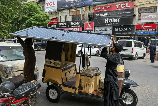 2025年6月23日，巴基斯坦卡拉奇，工人们将太阳能电池板装载到一辆自动人力车上。视觉中国 资料图