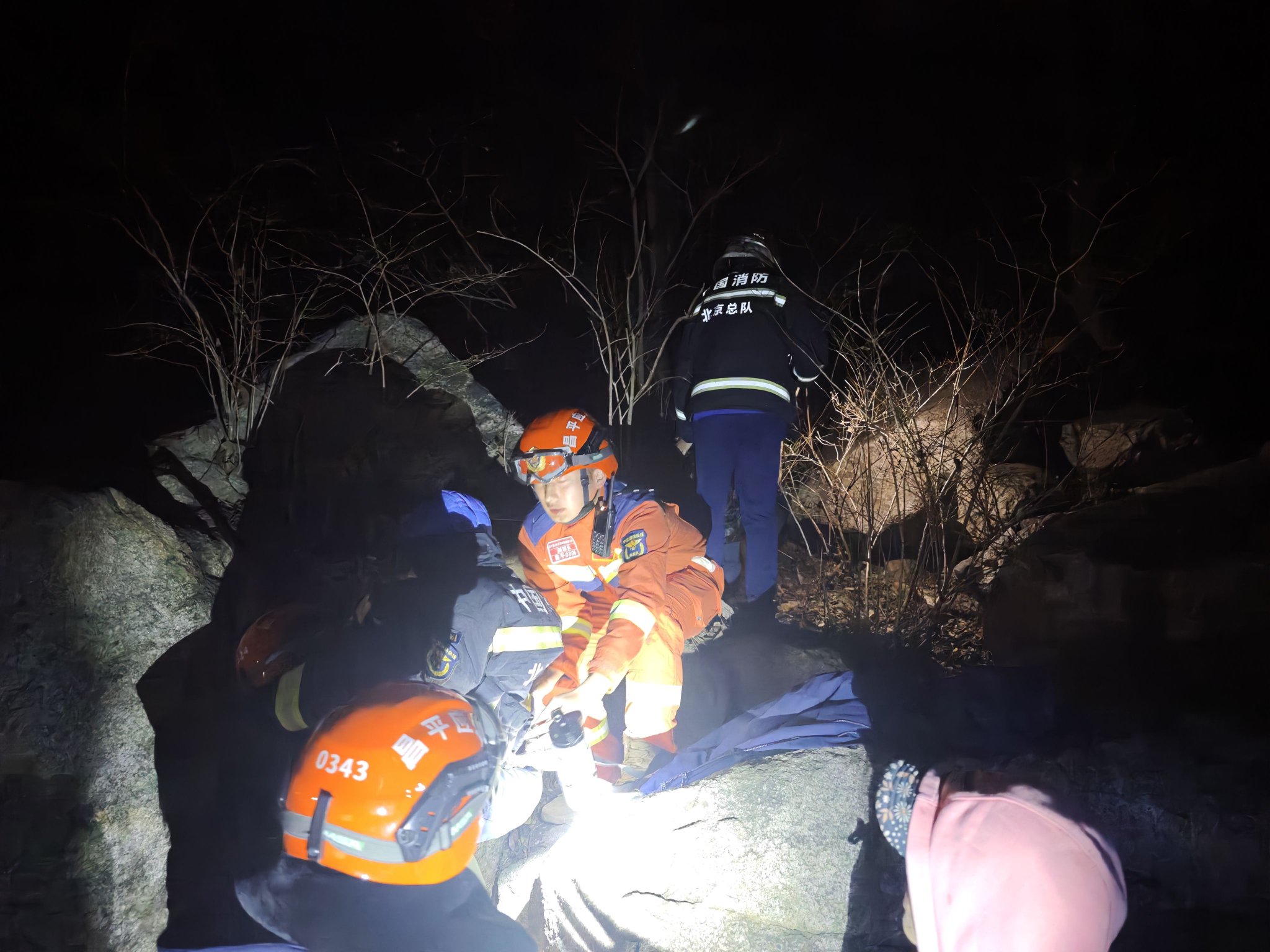 夜間進山救援，只能依靠頭燈和手電進行照明。遇到亂石，消防員通過後，再協助被救人員通過。 受訪者供圖