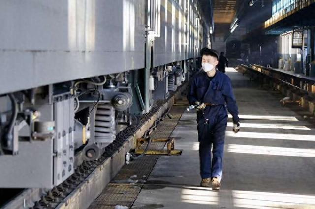 一名职工正拿着手电筒查看列车底部。中青报·中青网记者 董时/摄