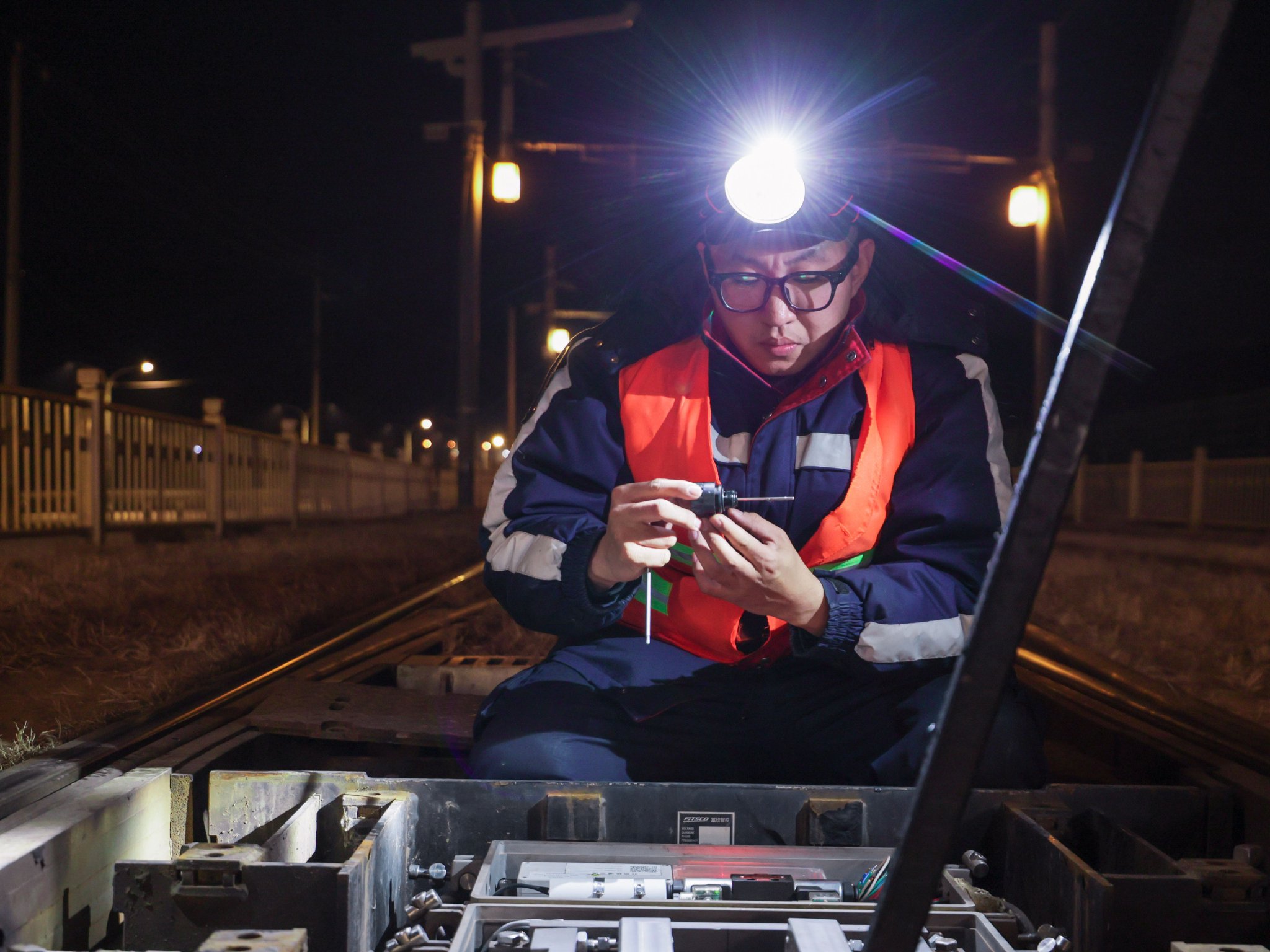 北京有軌電車西郊線通號維修班組維修工白子鵬蹲在地上檢修設備。董萬鑫 攝