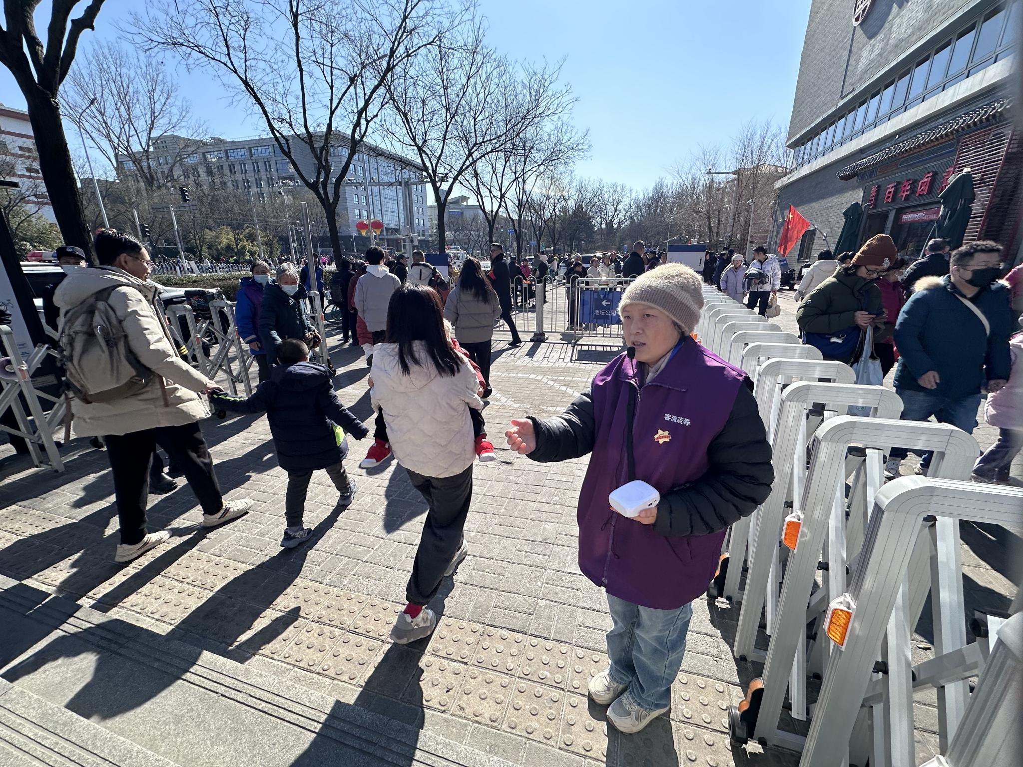 在地面出站口，客流疏導員許會俠提醒遊客注意安全。新京報記者 裴劍飛 攝