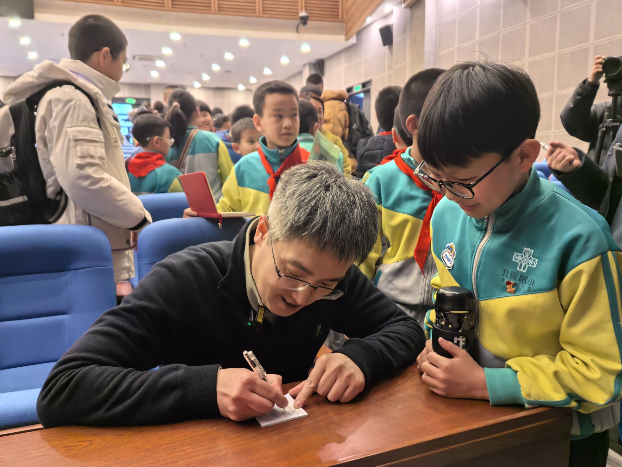 講座結束後，劉若川被小學生圍住，認真給孩子們簽名。新京報記者 楊菲菲 攝