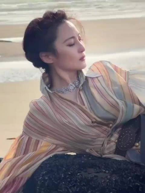 蒋勤勤一身条纹轻纱连衣裙，俯身在礁石上，海风吹动裙摆看起来就是海上神女！