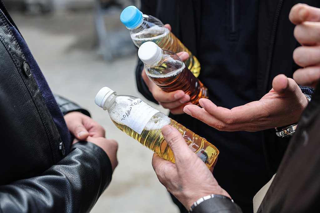 当地时间2026年3月17日，伊拉克埃尔比勒，民众手持瓶装燃油在石油市场议价。