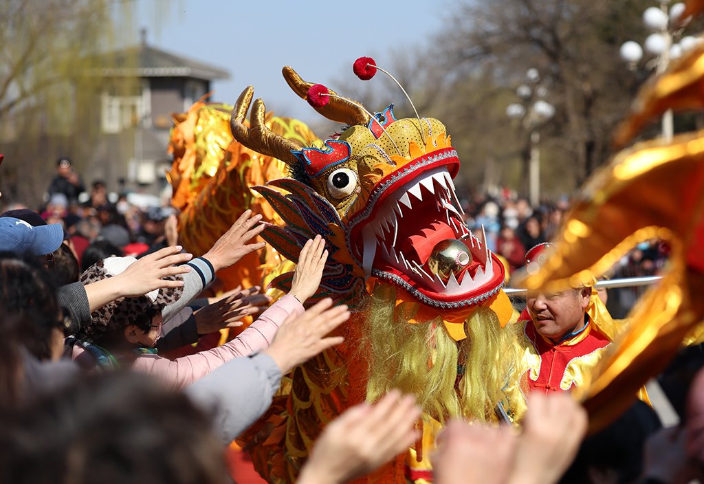 3月20日是春分节气，也是农历二月初二，在天津水上公园，观众在观看舞龙表演时摸龙头互动。