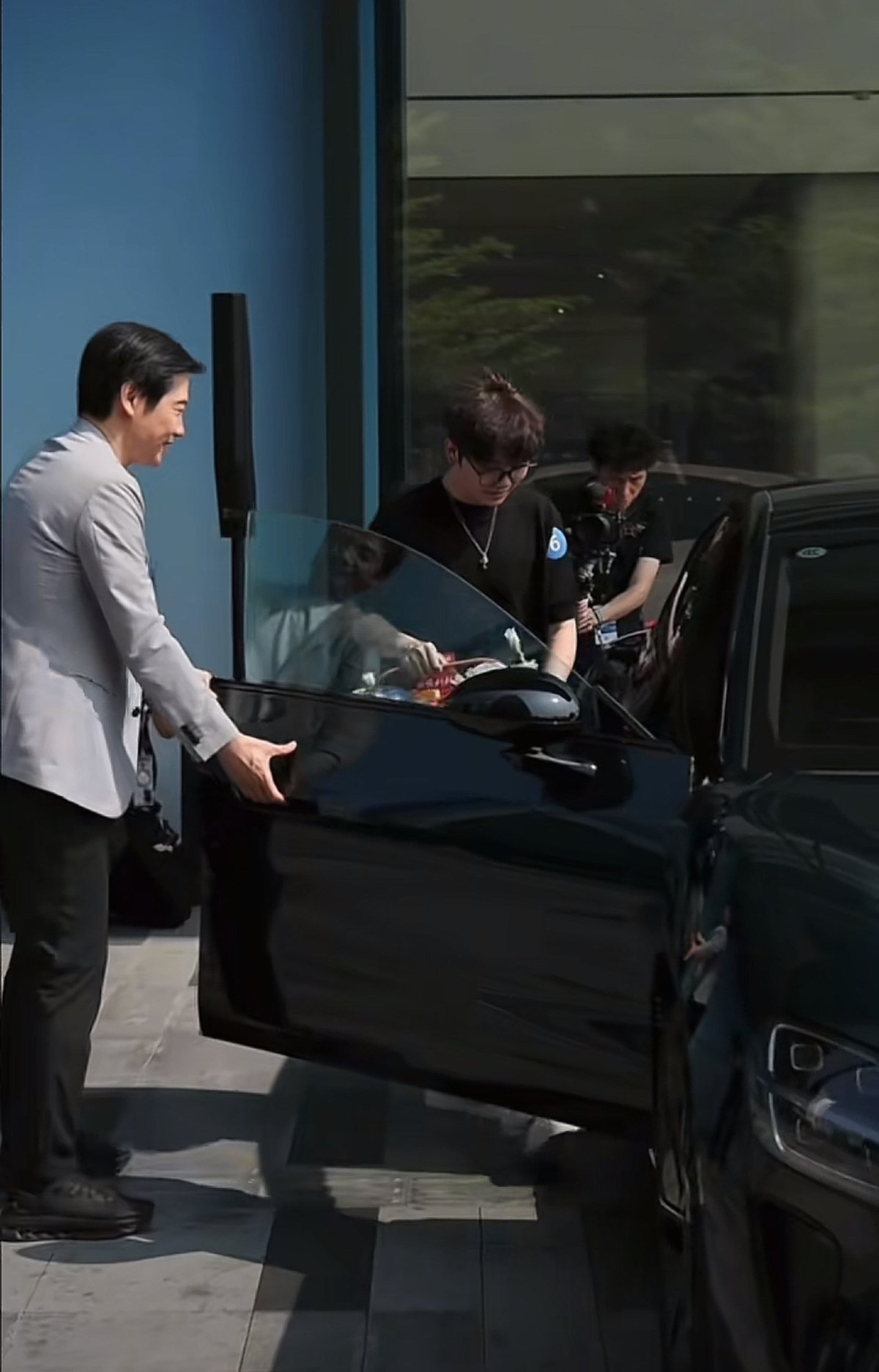 雷军为新一代小米SU7首批车主开门，双手合十表示感谢，目送车主离场，代言人苏炳添也现身