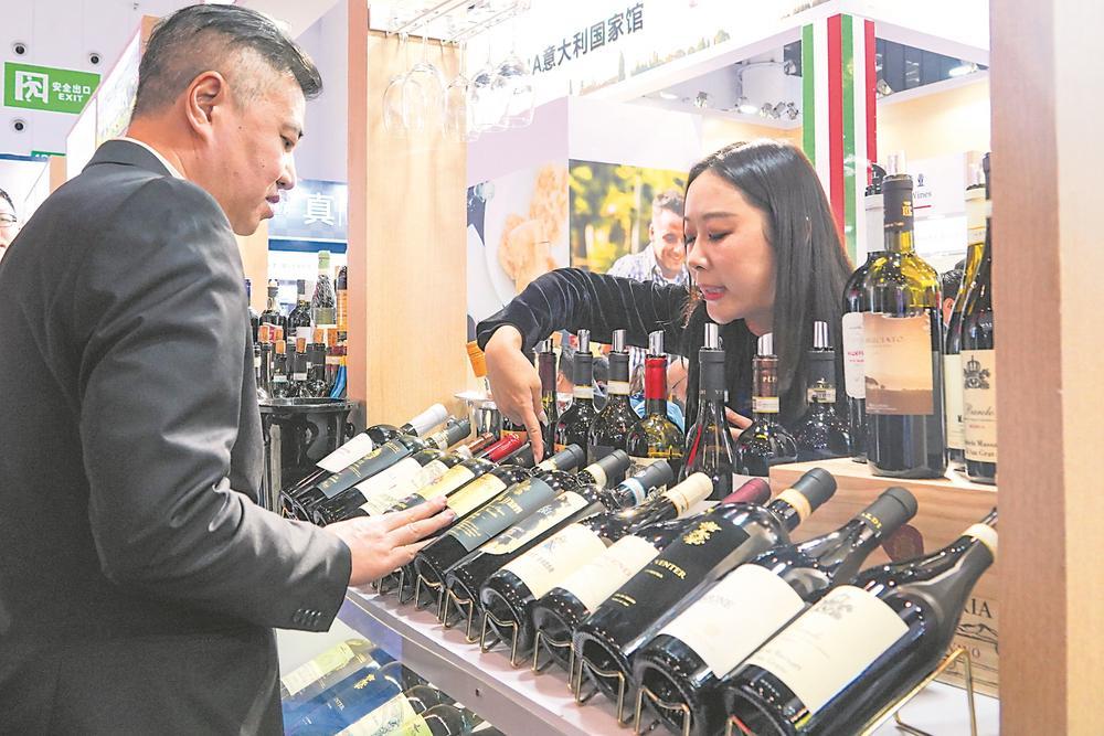 春糖会上参展商向客户介绍进口红酒。