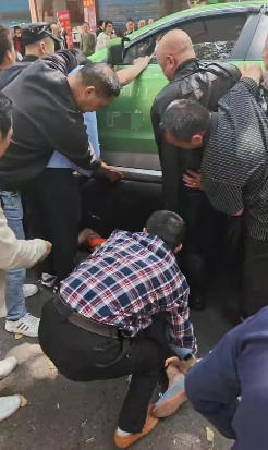 “救人要紧！”老人过马路时发生车祸被困出租车底，十余名热心群众抬车救人
