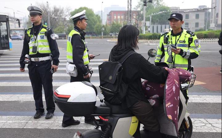 一位市民在騎行電動單車時因單手脫離車把接打電話，被交警處罰。新京報記者 王貴彬 攝