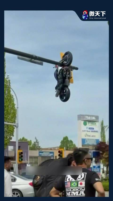 加拿大路口一摩托撞轿车瞬间被甩飞，竟整辆挂在交通灯杆上