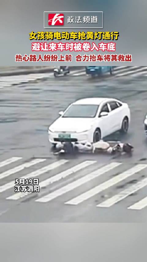 女孩骑电动车抢黄灯通行，避让来车时被卷入车底，热心路人纷纷上前 合力抬车将其救出