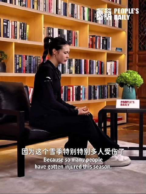 谷爱凌坐在书架前，认真分享各个雪上项目的相关见解