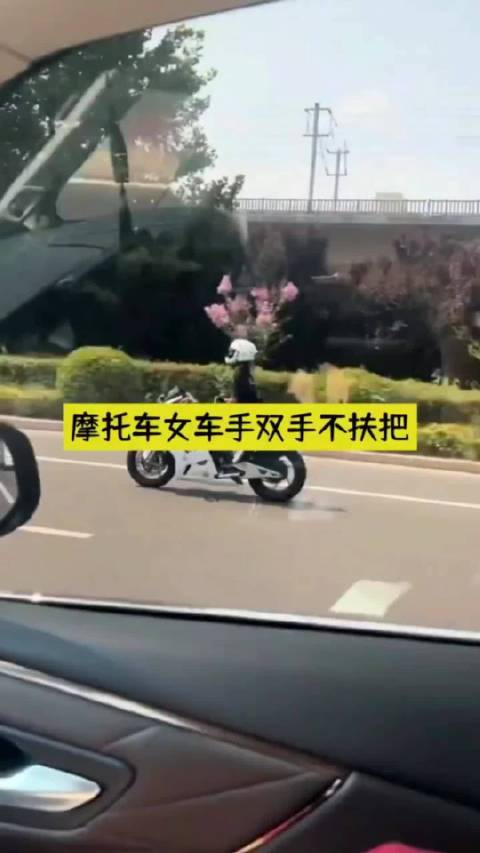 摩托车女车手双手不扶把翻看手机