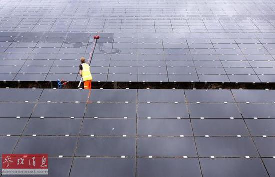 资料图片：英国牛津郡的一名工人在清洗太阳能电池板（美国雅虎新闻网站）