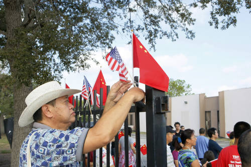 在美国休斯敦中国人活动中心,一位老华侨在围栏上插上中美两国国旗.