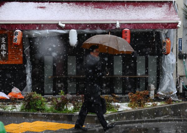 资料图片:在日本东京,行人从一家居酒屋前走过。(新华社)
