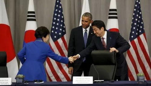 2016年3月31日,时任韩国总统朴槿惠(左)和日本首相安倍晋三(右)在时任美国总统奥巴马(中)的注视下握手。新华社/路透