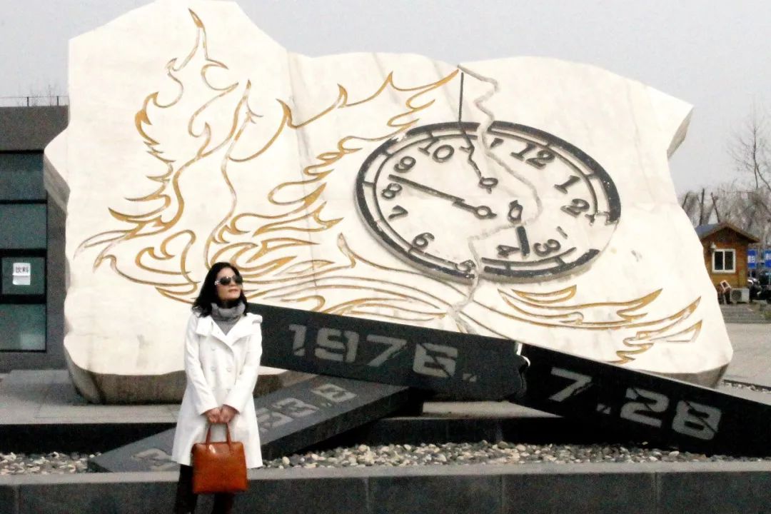  董惠娟在唐山地震遗址纪念公园入口与钟表雕塑的合影。新华社发
