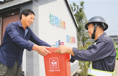 八月十三日,浙江省德清县新安镇的垃圾收集员陈连根(图右),在该镇新桥村青虾养殖户的养殖基地,收集农业有害垃圾。 姚海翔摄(人民图片)
