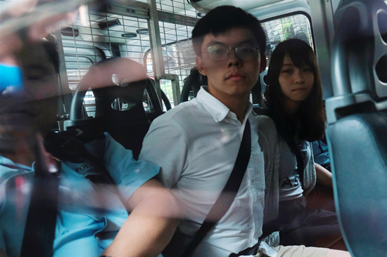 圖為黃之鋒(中)8月30日被捕,由警車押送到東區裁判法院提堂。