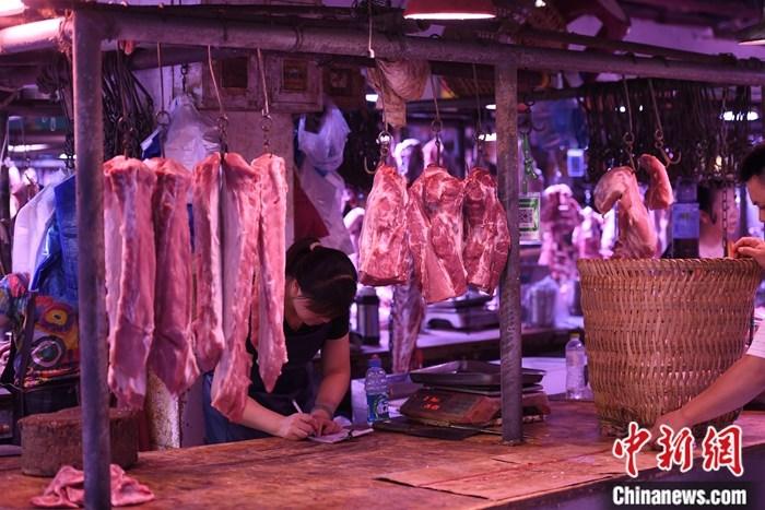资料图：一农贸市场内的商家挂满充足的猪肉。中新社记者 陈超 摄