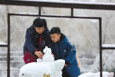 圆明园,一老一少在堆雪人。新京报记者 郑新洽 摄