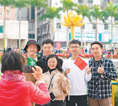 在金莲花广场,游人手举国旗区旗拍照留影。翁奇羽摄(人民视觉)