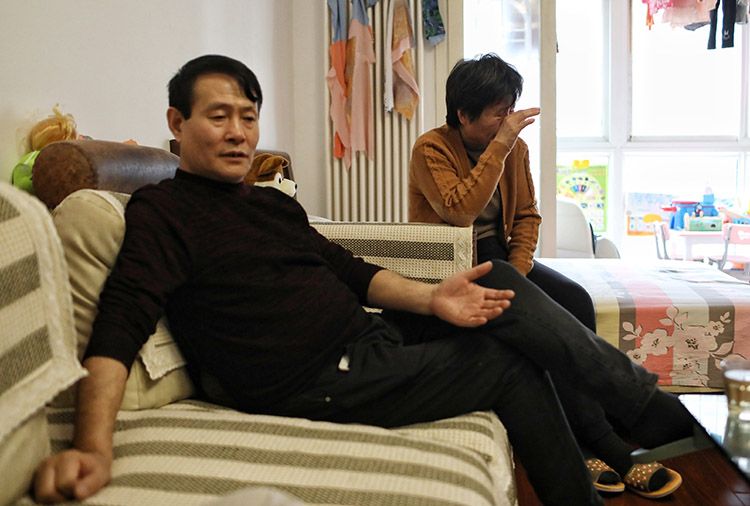 张英父亲在家中叙述案件过程,母亲在身后擦拭眼泪。