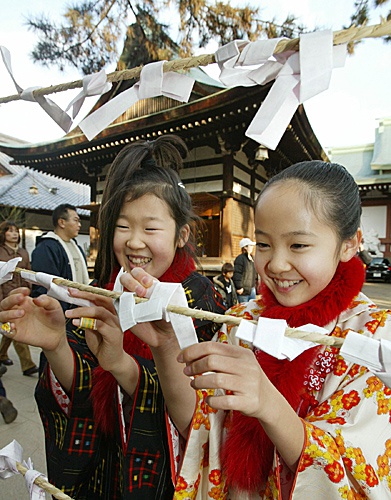 2004年1月1日,小姑娘在日本京都的一个神殿中将许愿结系在绳子上,祈求新年好运。(新华社)