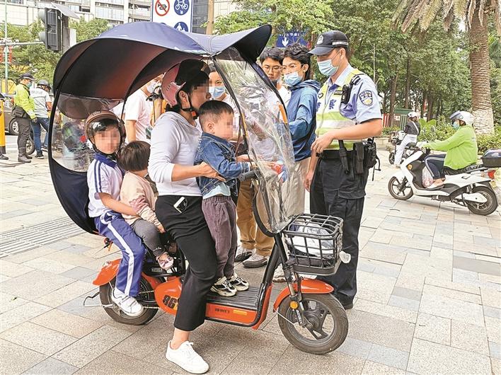 有市民驾驶电动自行车搭载3名小孩，2名未佩戴头盔，且擅自安装遮阳篷。 深圳晚报记者 高灵灵 摄