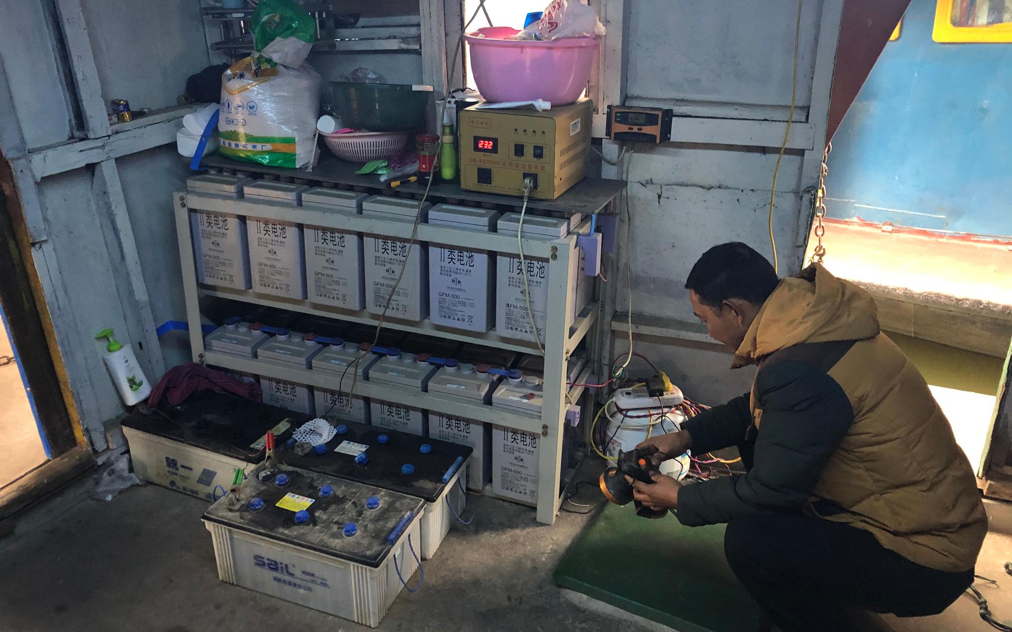 胡存库在船上给灯充电。为了用上稳定的电源,他在两年前购入了这些蓄电池。新京报记者 韩沁珂 摄