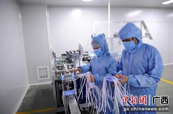 图为卢凤平(左)在生产医用外科口罩。蒋雪林 摄
