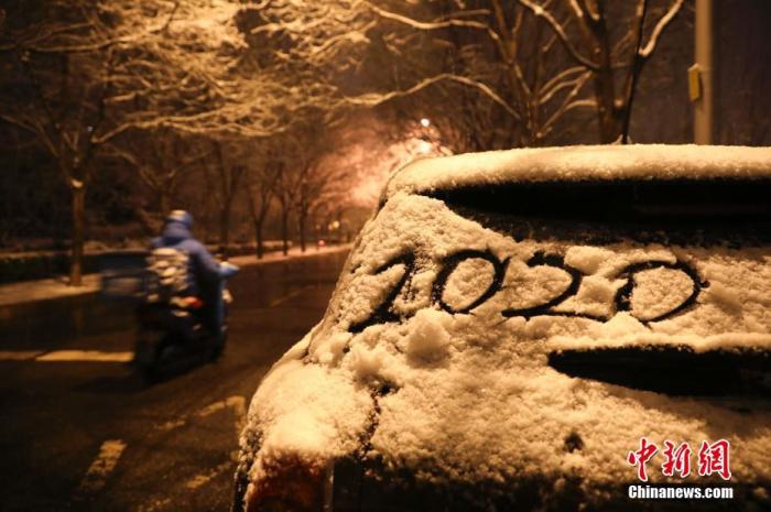 1月5日晚,北京迎来2020年第一场雪。图为民众冒雪出行。 中新社记者 赵隽 摄