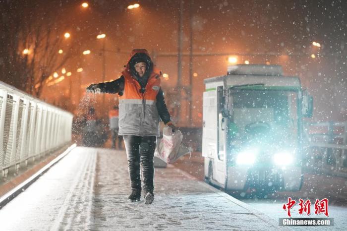 1月5日晚,北京迎来2020年首场降雪。图为环卫工人撒融雪剂,防止道路结冰。 中新社记者 张兴龙 摄 中新社记者 张兴龙 摄
