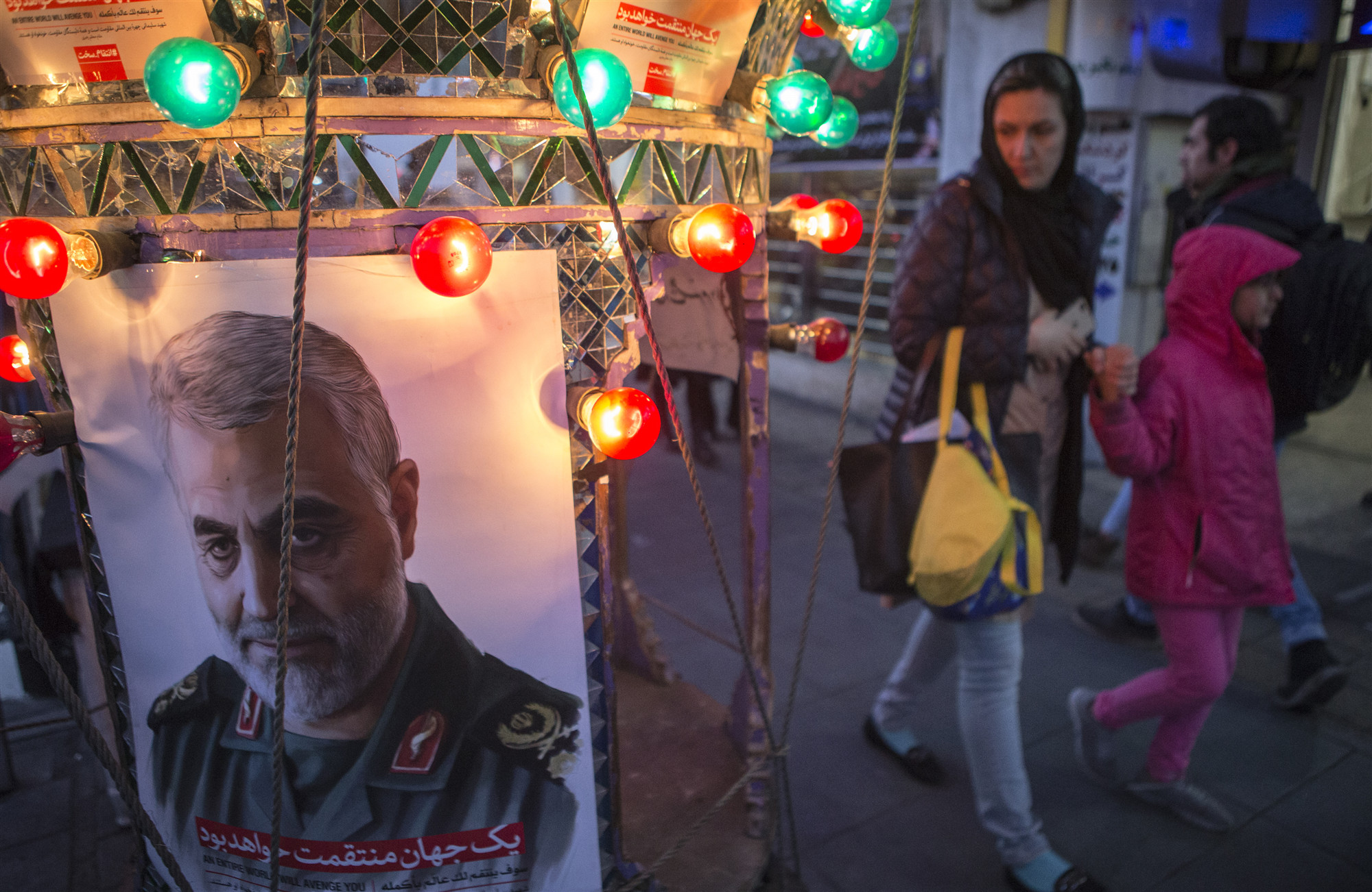 ▲1月5日，在伊朗首都德黑兰，人们走过悼念苏莱曼尼的海报。|新华社